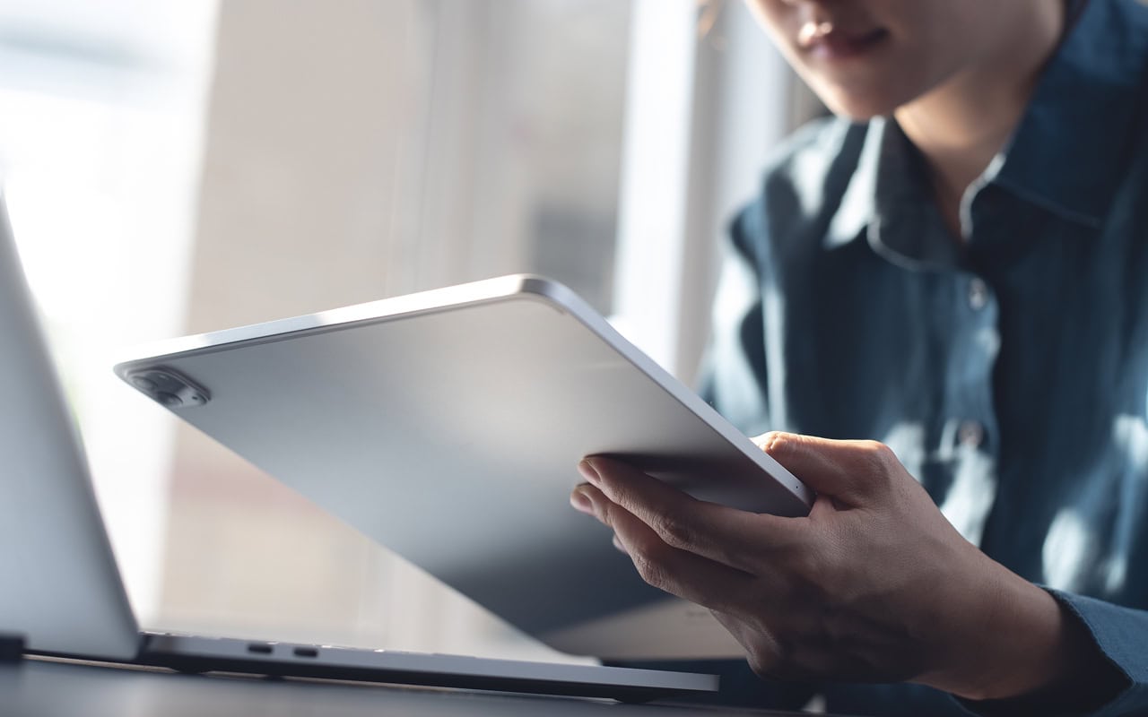 A woman is using a tablet computer while sitting at a desk.