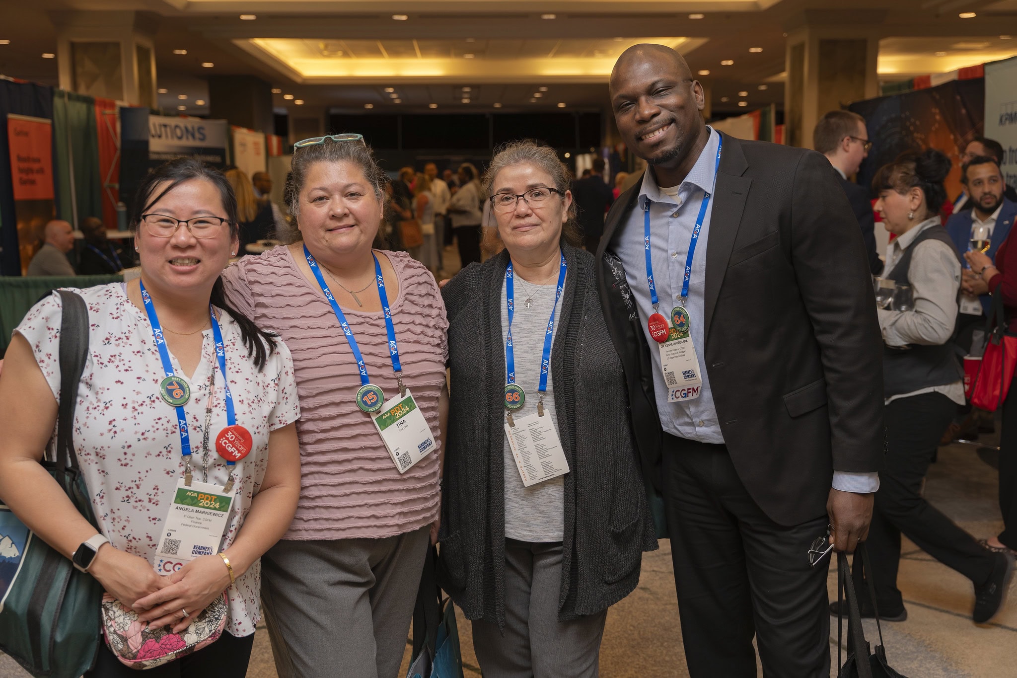 A group of four AGA event attendees stand shoulder-to-shoulder, excited to be in the Solutions Hall at PDT