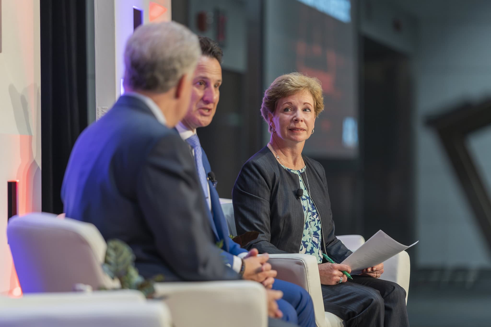 Ann Ebberts, CEO of AGA sit on stage at Fraud 24 holding a set of papers while talking to two IGs from the Federal Government.