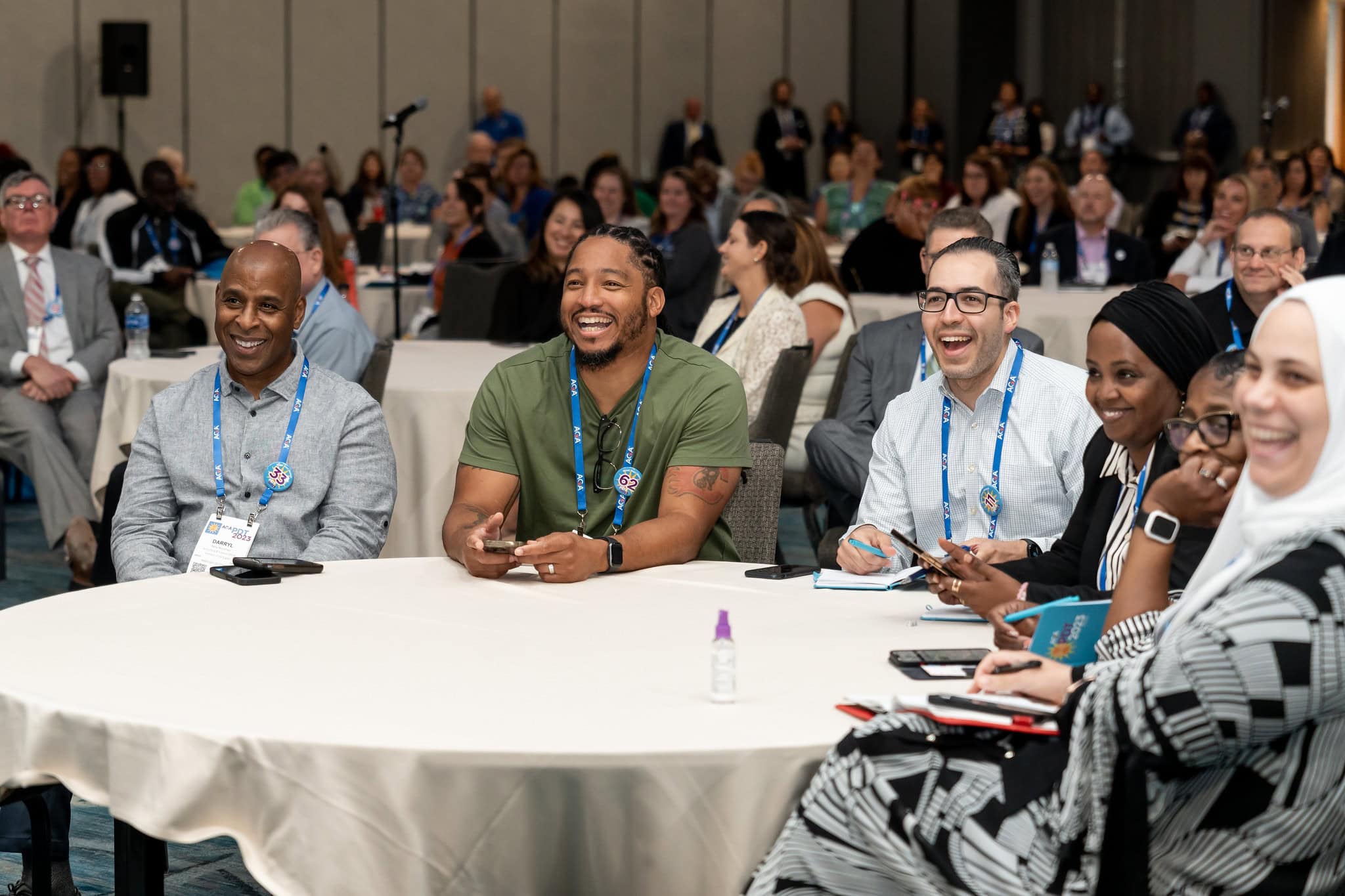 A group of AGA attendees sit around a table at a training event, smiling and seemingly enjoying the session