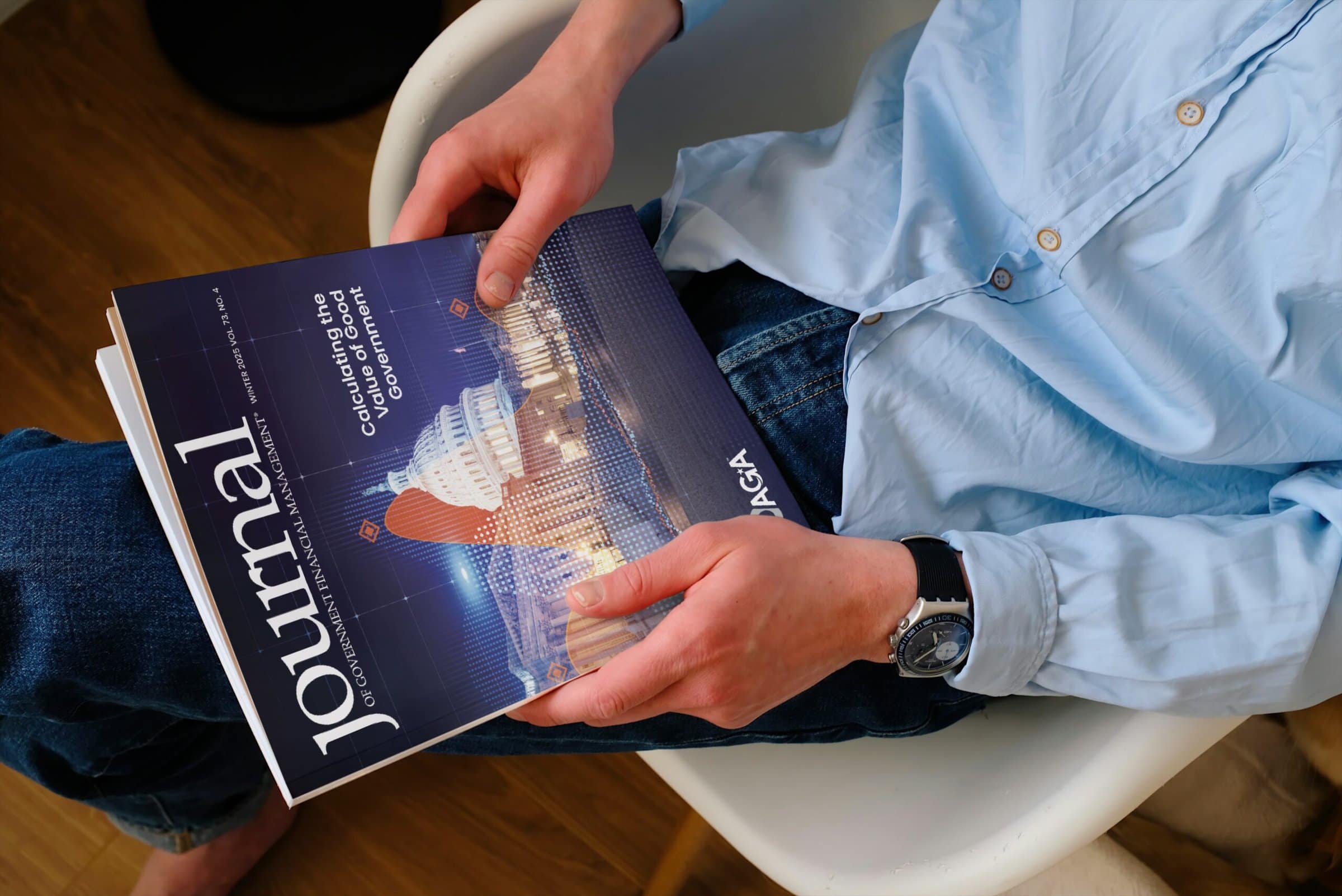 An overhead shot of a copy of the Journal. held by a man in a blue button down shirt and jeans