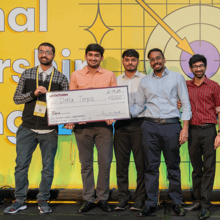 Datathon winners stand on stage at NLT '25 holding their prize check